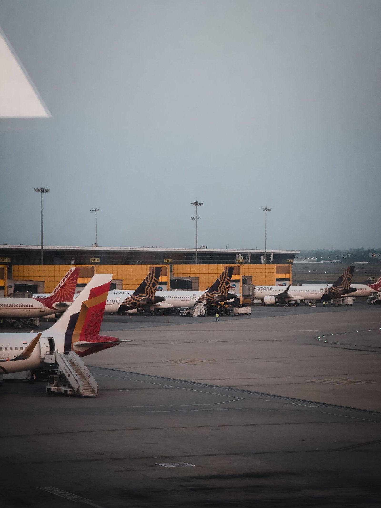 Multiple airplanes on the tarmac at Delhi airport with a clear view of the terminal.